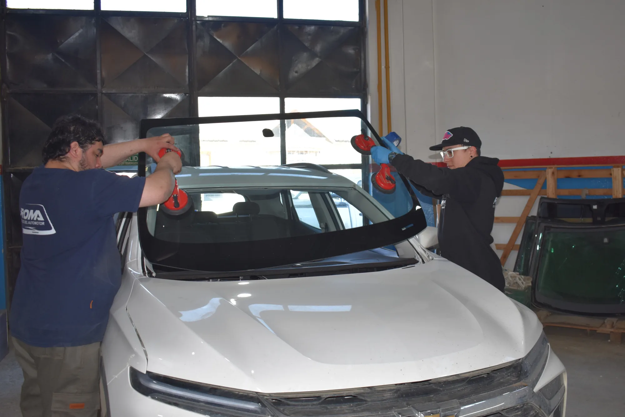 Dos técnicos de ROMA colocando un parabrisas en una camioneta