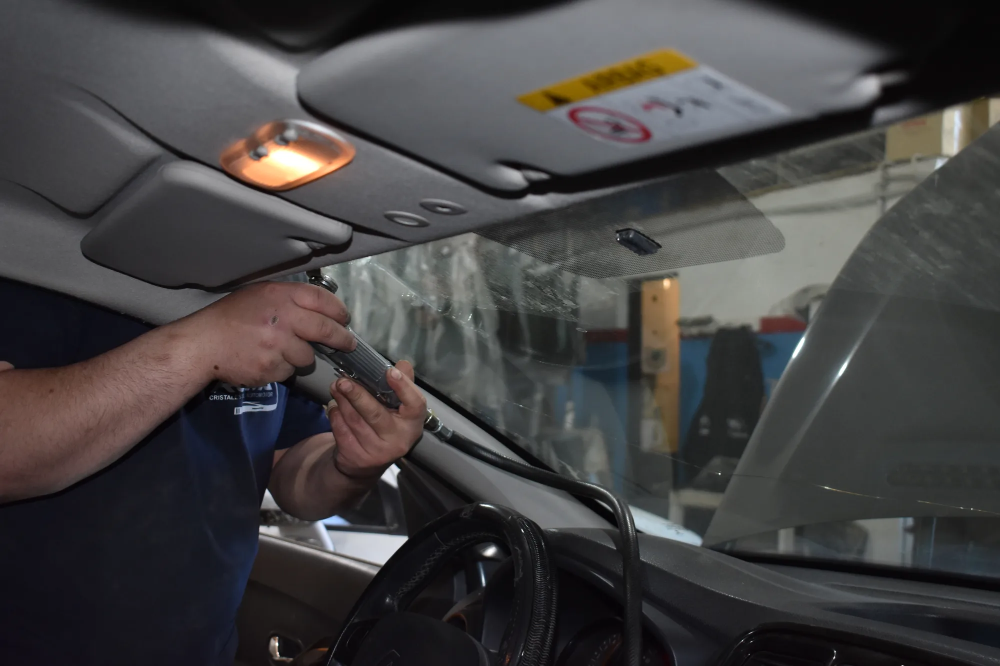 Técnico trabajando desde el interior del vehículo para retirar el parabrisas