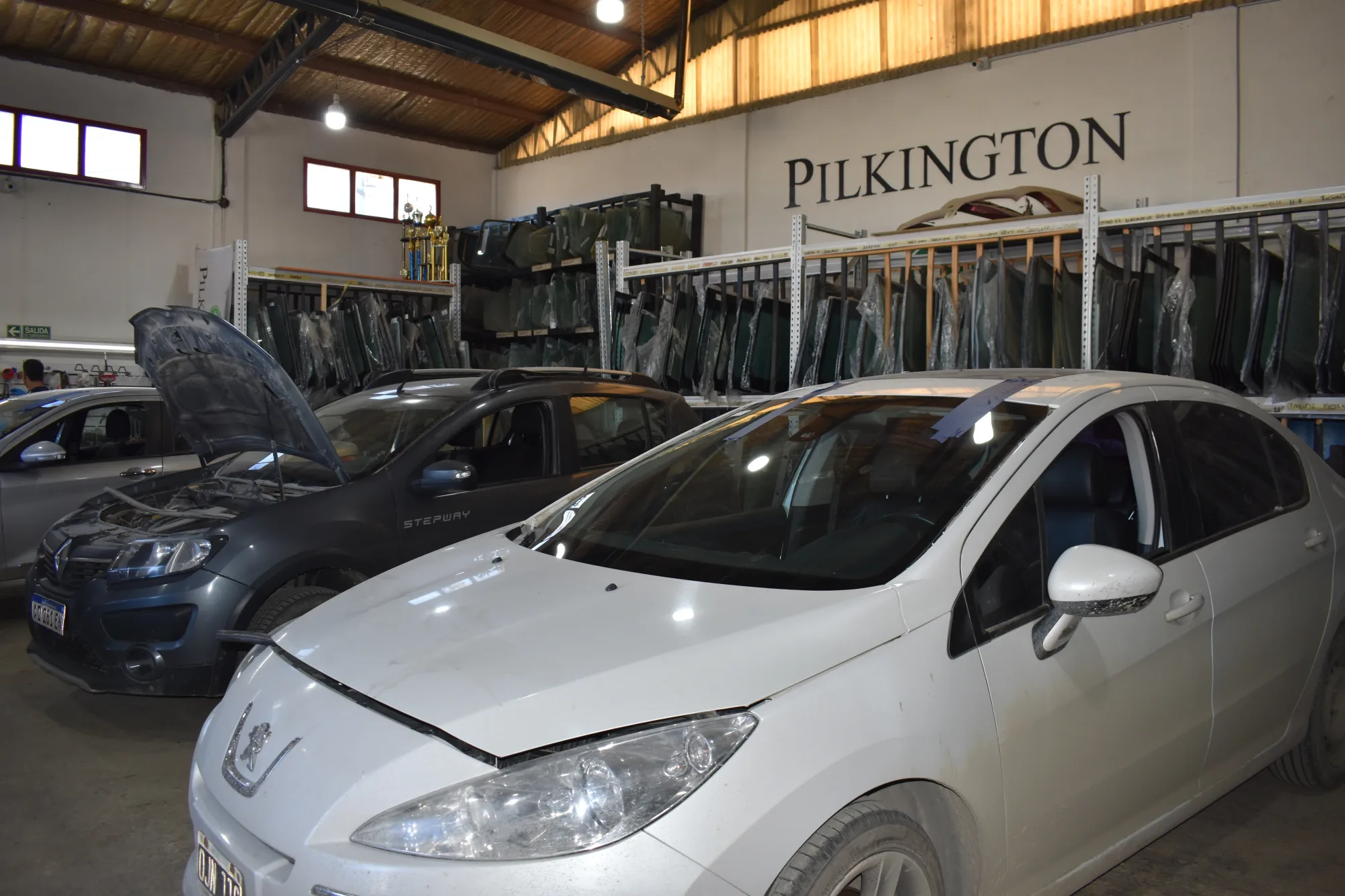 Interior del taller con el cartel de Pilkington y estanterías de cristales
